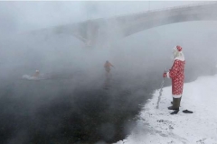 A man dressed as Ded Moroz, the Russian equivalent of Santa Claus, watches Ivan Abrosimov, 80, (L) and Nikolay Bocharov, 78, members of the Cryophile amateurs winter swimmers club, taking a bath in the icy waters of the Yenisei River during the celebrations for the upcoming Christmas and New Year, with the air temperature at about minus 34 degrees Celsius (minus 29.2 degrees Fahrenheit), in Krasnoyarsk, Russia, December 24, 2016. REUTERS/Ilya Naymushin - RTX2WD61