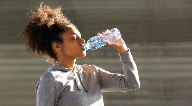 African american sports woman drinking from water bottle