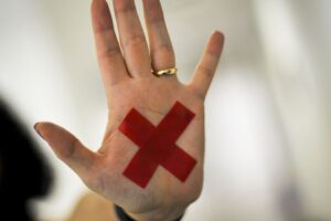 O sinal “X” feito com batom vermelho (ou qualquer outro material) na palma da mão ou em um pedaço de papel, o que for mais fácil, permite que a pessoa treinada reconheça que aquela mulher foi vítima de violência doméstica e, assim, acione a Polícia Militar.