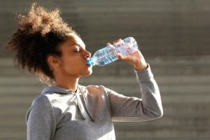 African american sports woman drinking from water bottle